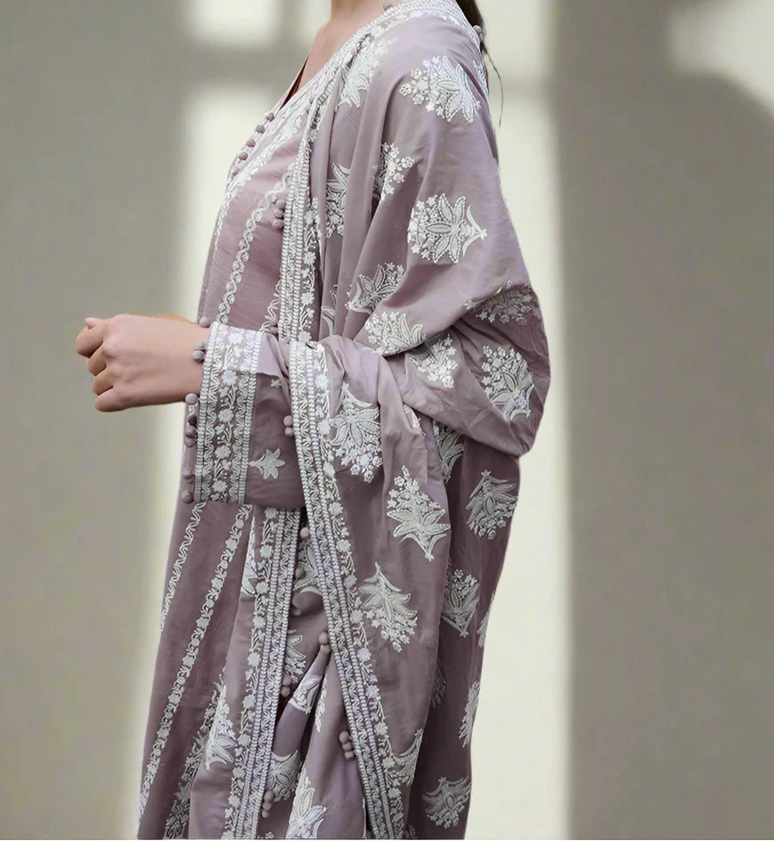 Woman wearing a light purple traditional outfit with white floral embroidery against a neutral background